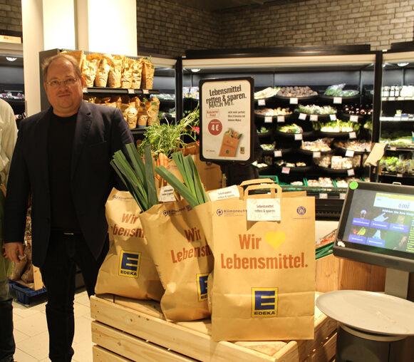 Kay Hollender und sein Abteilungsleiter der Obst- und Gemüseabteilung präsentieren die Lebensmittel-Retter-Tüten