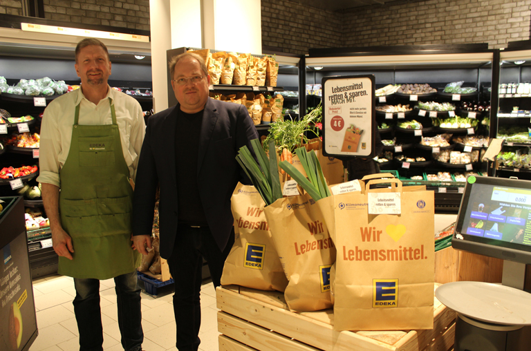 Kay Hollender und sein Abteilungsleiter der Obst- und Gemüseabteilung präsentieren die Lebensmittel-Retter-Tüten