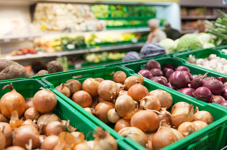 Verschiedene Zwiebelsorten in grünen Plastikkisten in der Obst- und Gemüseabteilung